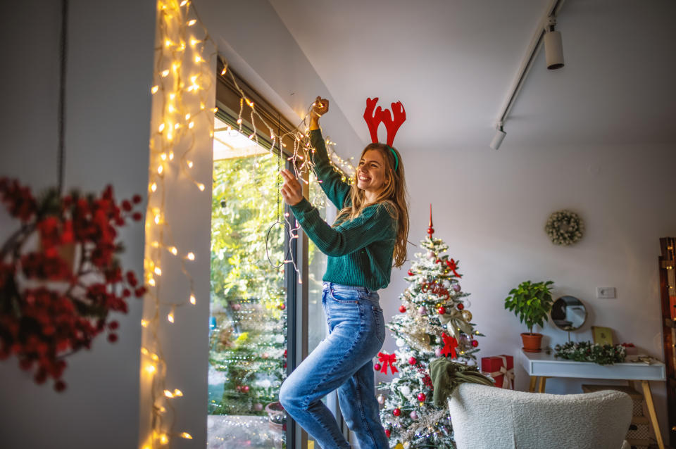 Woman putting up Christmas lights. (Getty Images)