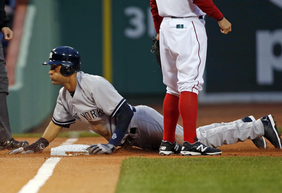 New York Yankees' Derek Jeter slides safely into third base on a passed ball and throwing error by Boston Red Sox catcher A.J. Pierzynski during the first inning of a baseball game at Fenway Park in Boston, Tuesday, April 22, 2014. (AP Photo/Elise Amendola)