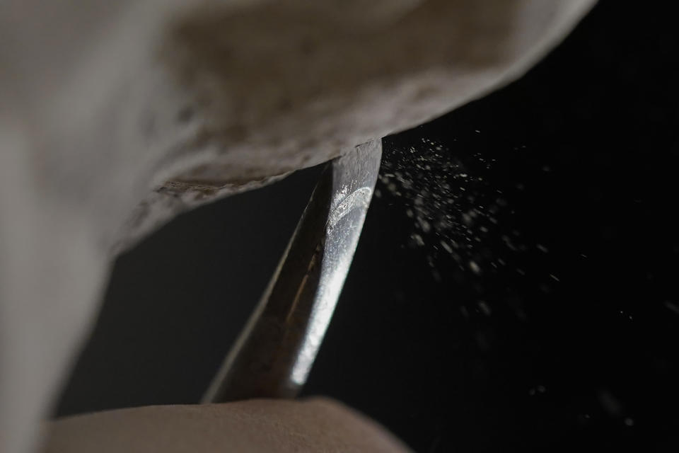 Limestone dust falls as Sean Callahan uses a chisel to work on a carving of Holocaust survivor and Nobel Peace Prize winning author Elie Wiesel in the Human Rights Porch at the Washington National Cathedral, Thursday, March 25, 2021. (AP Photo/Carolyn Kaster)