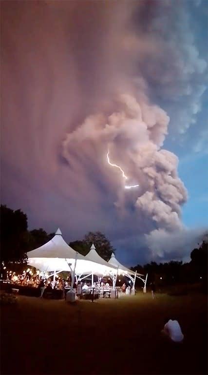 General view of a wedding ceremony as Taal Volcano sends out a column of ash in the background, in Alfonso