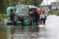 People push an auto rickshaw through a flooded road as a school boy rides his bicycle behind in Bagha area in Sylhet, Bangladesh, Monday, May 23, 2022. Pre-monsoon deluges have flooded parts of India and Bangladesh, killing at least 24 people in recent weeks and sending 90,000 people into shelters, authorities said Monday. (AP Photo)