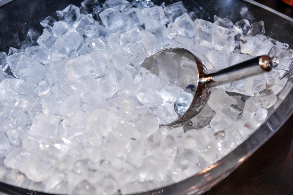 A metal scoop resting in a large tub filled with ice cubes