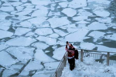 A pedestrian stops to take a photo by Chicago River, as bitter cold phenomenon called the polar vortex has descended on much of the central and eastern United States, in Chicago, Illinois, U.S., January 29, 2019. REUTERS/Pinar Istek TPX IMAGES OF THE DAY