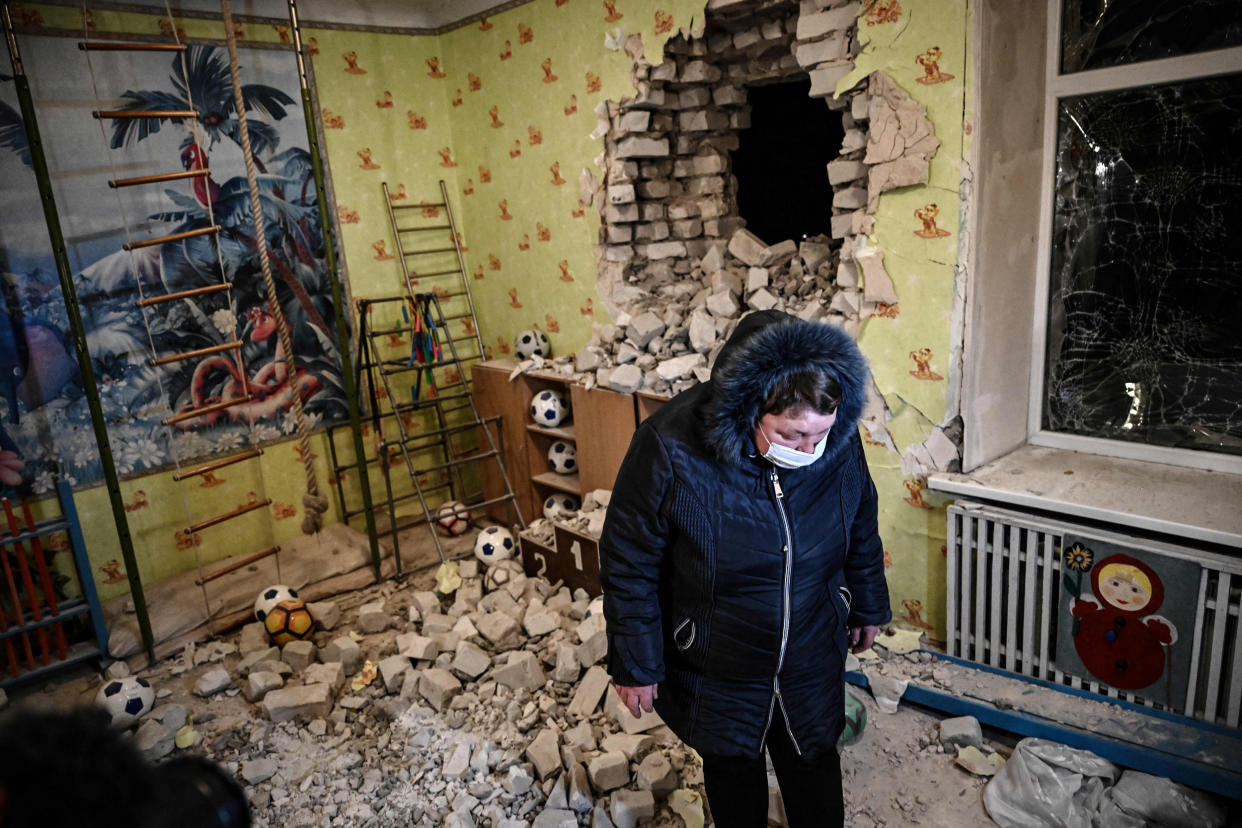 A woman stands among debris of the reported shelling of a kindergarten (Aris Messinis  / AFP via Getty Images file)