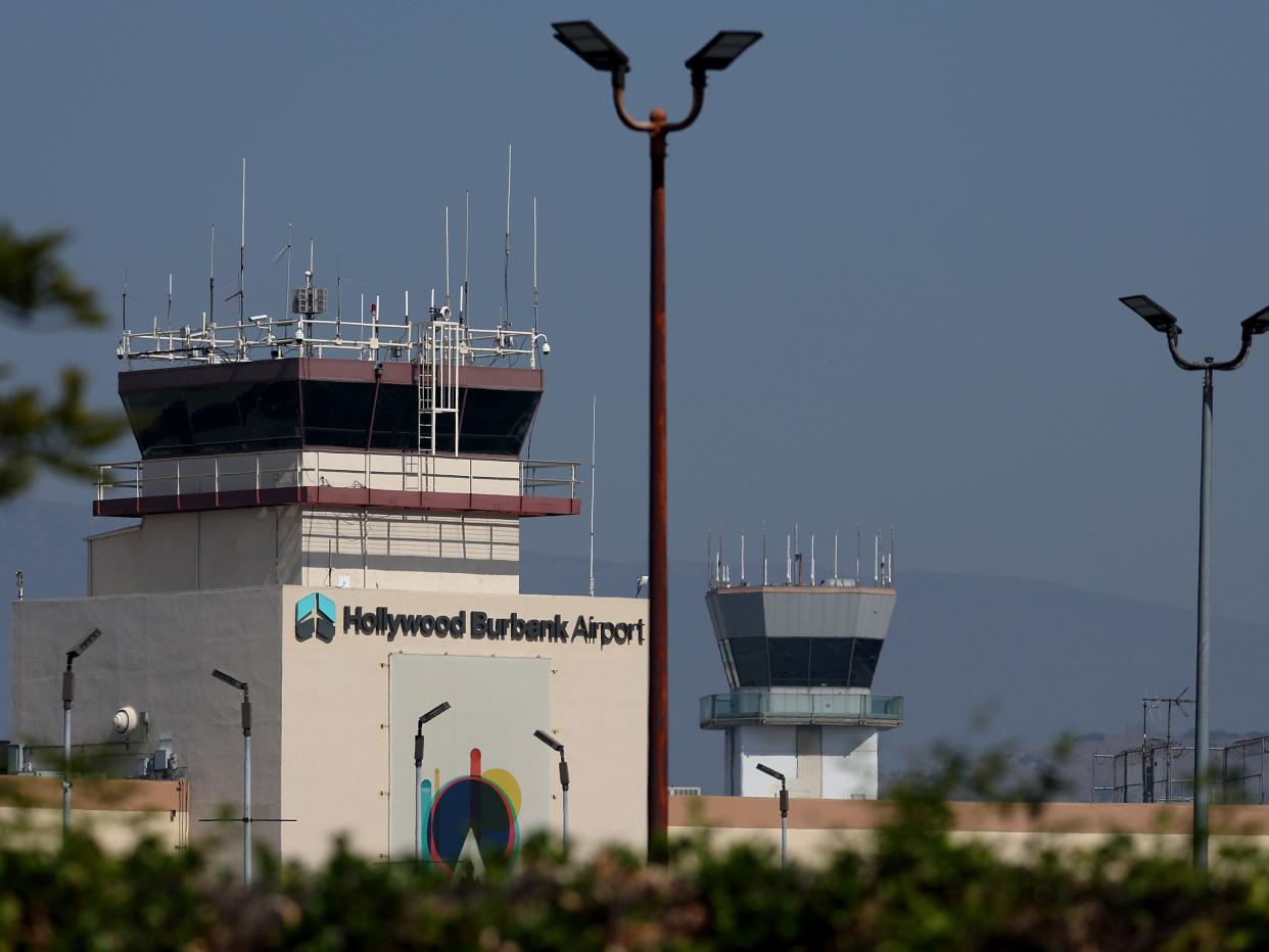 A view of control towers at Hollywood Burbank Airport with foliage in the foreground