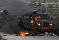 FILE - In this Wednesday, March 27, 2019 file photo, Israeli border policemen move away from a burning vehicle during clashes with Palestinians at checkpoint Bet El near the West Bank city of Ramallah. The conflict with the Palestinians has been a central issue in Israeli elections going back decades, but in the campaign ahead of next week's vote it's been notably absent. Prime Minister Benjamin Netanyahu's ruling Likud Party has offered no plan for what many believe is the country's most existential problem. His main challenger speaks vaguely of "separation," while Netanyahu's hard-line partners speak openly of the once unthinkable idea of annexing all or parts of the West Bank. (AP Photo/Majdi Mohammed, File)