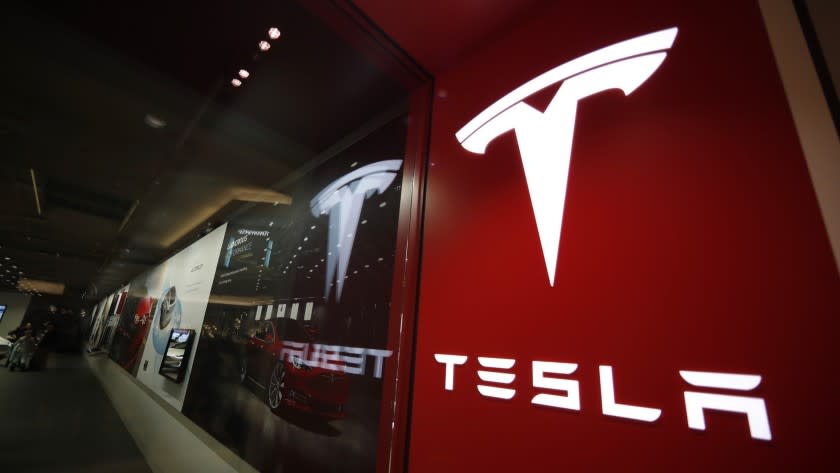 FILE- In this Feb. 9, 2019 file photo, a sign bearing the company logo is displayed outside a Tesla store in Cherry Creek Mall in Denver. A new automatic lane-change feature of Tesla's Autopilot system doesn't work well and could be a safety risk to drivers, according to tests performed by Consumer Reports. Senior Director of Auto Testing Jake Fisher said in a statement Wednesday, May 22, that the system doesn't appear to react to brake lights or turn signals, and it can't anticipate what other drivers will do. (AP Photo/David Zalubowski, File)