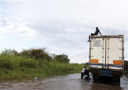 A man sits atop a truck as they remain stranded in a flooded section of the road as they drive from the Ugandan border into South Sudan at Nimule August 27, 2013. REUTERS/Andreea Campeanu