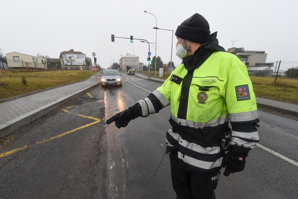 A police officer stops a car on a road between the towns, Ostrava and Opava, near Dehylov, Czech Republic Monday, March 1, 2021. Limits for free movement of people are set in the Czech Republic. Travelling to other counties unless the go to work or have to take care about relatives is prohibited. (Jaroslav Ozana/CTK via AP) ** SLOVAKIA OUT **