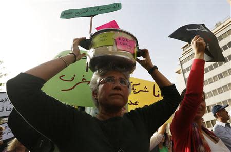 A woman holds a pressure cooker during a march against domestic violence against women, marking International Women's Day in Beirut March 8, 2014. REUTERS/Jamal Saidi