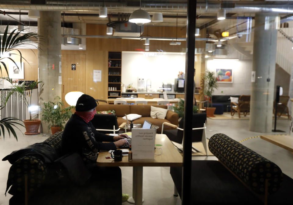 A man wearing a face mask works in his computer at a coffee shop downtown Prague, Czech Republic, Tuesday, Oct. 13, 2020. The Czech Republic is imposing a new series of restrictive measures in response to a record surge in coronavirus infections. Prime Minister Andrej Babis says that all bars, restaurants and clubs will be closed, starting on Wednesday Oct. 14, 2020, while drinking of alcohol is banned at public places.(AP Photo/Petr David Josek)