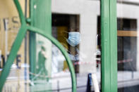 A cafe employee, Djibril, cleans the window of a closed cafe, in Paris, Monday, June 1, 2020. Parisians who have been cooped up for months with take-out food and coffee will be able to savor their steaks tartare in the fresh air and cobbled streets of the City of Light once more -- albeit in smaller numbers. (AP Photo/Thibault Camus)