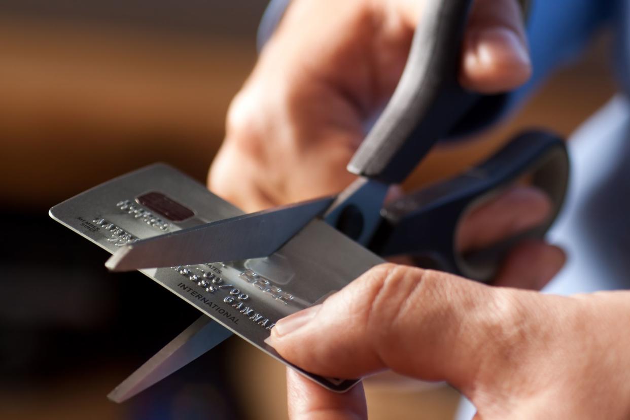 Male hands cutting a credit card with scissors. Numbers and letters have been jumbled and altered beyond any resemblance to the original card. You may also like: