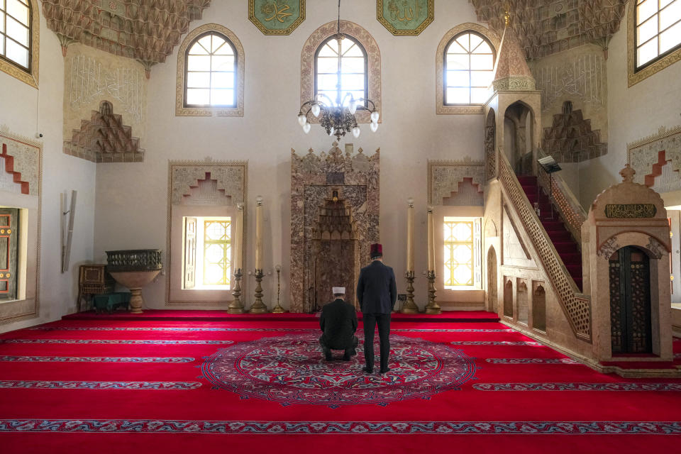 In this Thursday, April 9, 2020 photo two clerics pray inside the 16th century built Gazi Husrev-beg Mosque in Sarajevo, Bosnia, as worshipers stay away due to the national lockdown the authorities have imposed attempting to limit the spread of the new coronavirus. (AP Photo/Kemal Softic)