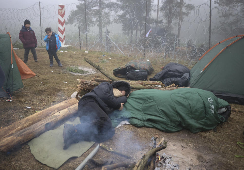 Migrants from the Middle East and elsewhere warm up at the fire gathering at the Belarus-Poland border near Grodno, Belarus, Thursday, Nov. 11, 2021. The European Union has accused Belarus' authoritarian President Alexander Lukashenko of encouraging illegal border crossings as a "hybrid attack" to retaliate against EU sanctions on his government for its crackdown on internal dissent after Lukashenko's disputed 2020 reelection. (Ramil Nasibulin/BelTA pool photo via AP)