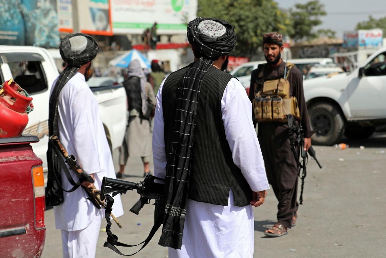 Taliban fighters stand guard in front of the Hamid Karzai International Airport in Kabul, Afghanistan, Monday, Aug. 16, 2021. Thousands of people packed into the Afghan capital's airport on Monday, rushing the tarmac and pushing onto planes in desperate attempts to flee the country after the Taliban overthrew the Western-backed government.