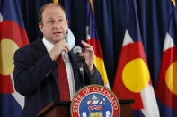 Colorado Governor Jared Polis pulls off his face mask as he makes a point during a news conference on the state's efforts against the new coronavirus Tuesday, July 21, 2020, in Denver. (AP Photo/David Zalubowski)