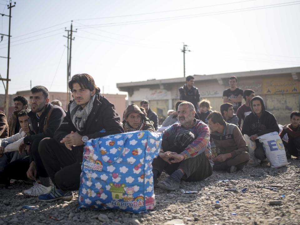 Iraqi men who have fled fighting between militants and Iraqi forces in Mosul are sequestered at a collection point in Gogjali, Iraq in this Nov. 12, 2016 photo. During their rule of Mosul, the Islamic State group brutally purged whole sectors of the once multicultural city, targeting Kurds, Shiite and Christians, hunting down former police and soldiers in their homes and hanging anyone caught with a mobile phone from lamp posts. (AP Photo/Nish Nalbandian)