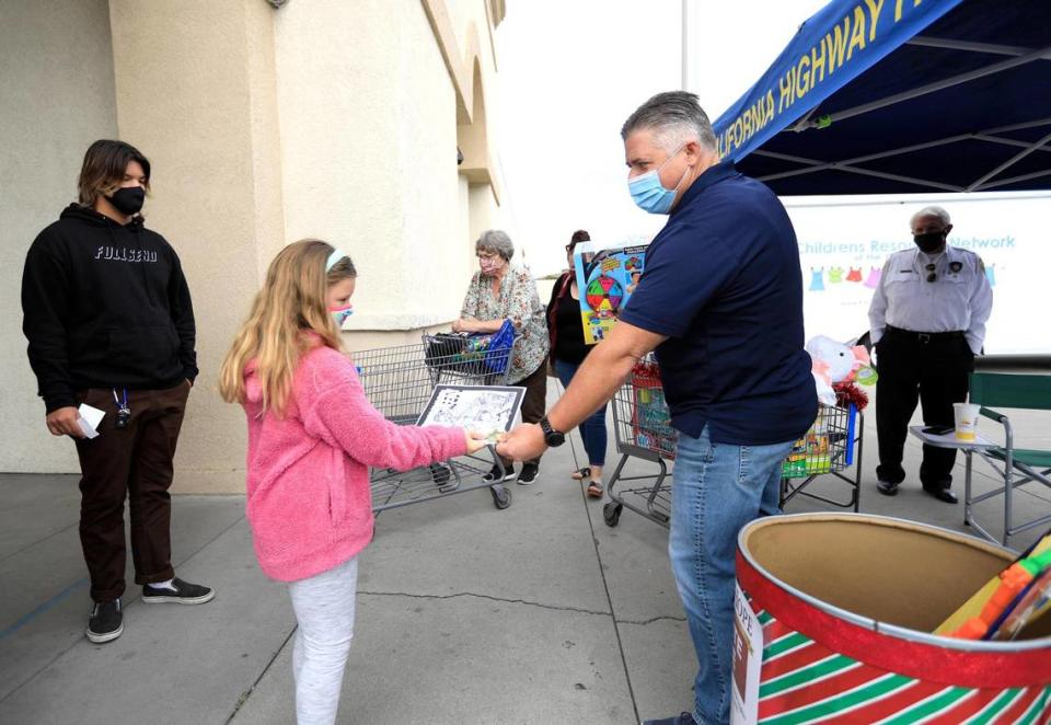 Mike Poelking, public affairs officer for the California Highway Patrol, accepts a new toy from a young shopper at the CHP booth next to Walmart in Arroyo Grande. People can drop off toys at Walmart stores in Arroyo Grande and Santa Maria.