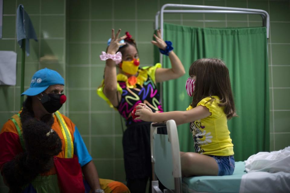 <span class="caption">A girl is entertained by clowns as she waits after being injected with a dose of the Soberana-02 vaccine for COVID-19 in Havana, Cuba, in August 2021.</span> <span class="attribution"><span class="source">(AP Photo/Ramon Espinosa)</span></span>