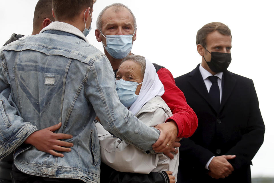 France President Emmanuel Macron, right, stands as Sophie Petronin, center, a French aid worker held hostages for four years by Islamic extremists in Mali, is greeted by relatives upon her arrival at the Villacoublay military airport near Paris, Friday Oct. 9, 2020. Sophie Petronin was released with three other hostages from Mali and Italy this week. Before leaving Mali's capital, she said she was doing well and wanted to return to Mali to resume her humanitarian work with malnourished children and orphans.(Gonzalo Fuentes, Pool Photo via AP)