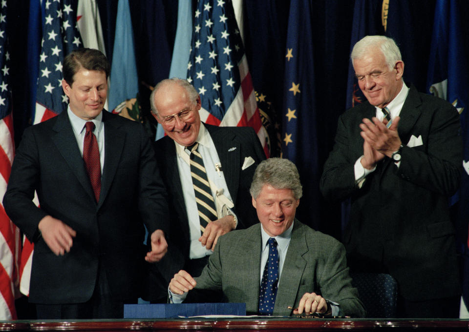 FILE - House Minority Leader Bob Michel of Ill., center, looks over President Bill Clinton's shoulder as the president signs legislation implementing the North American Free Trade Agreement, Dec. 8, 1993, at the Mellon Auditorium in Washington as Vice President Al Gore, left, and House Speaker Thomas Foley, of Wash., look on. (AP Photo/Doug Mills, File)