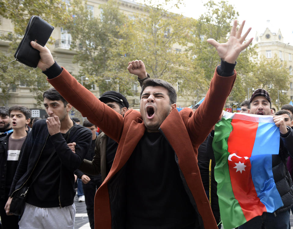 Azerbaijanis celebrate with national flags in Baku, Azerbaijan, Tuesday, Nov. 10, 2020. Armenia and Azerbaijan announced an agreement early Tuesday to halt fighting over the Nagorno-Karabakh region of Azerbaijan under a pact signed with Russia that calls for deployment of nearly 2,000 Russian peacekeepers and territorial concessions. (AP Photo)