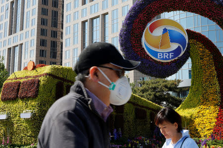 People walk past a flower installation marking the Belt and Road Forum in Beijing, China April 25, 2019. REUTERS/Florence Lo