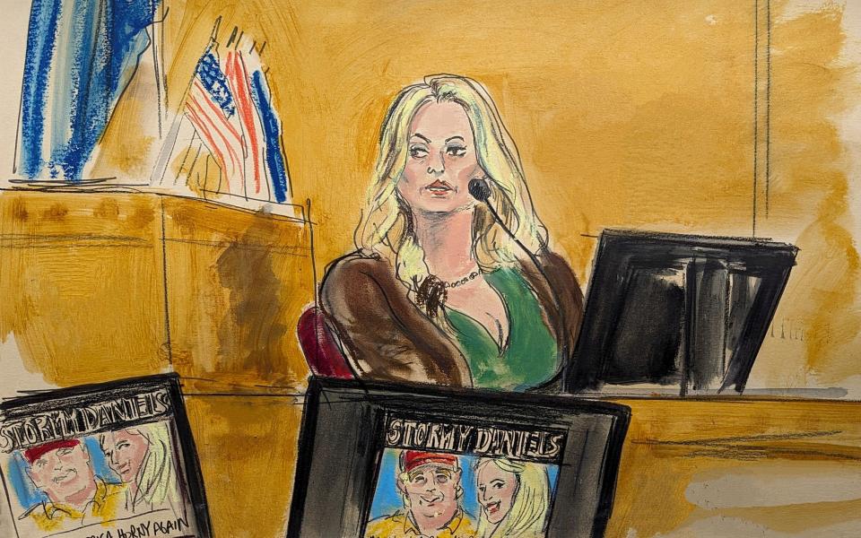 Stormy Daniels testifies on the witness stand as a promotional image for one of her shows featuring an image of Donald Trump is displayed in Manhattan Criminal Court