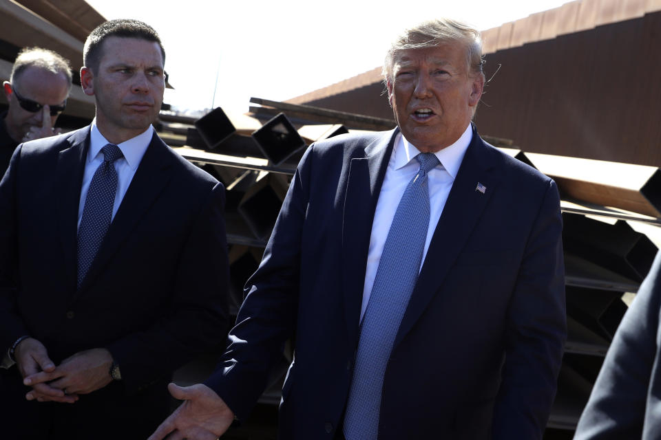 FILE - In this Sept. 18, 2019, file photo, President Donald Trump talks with reporters as he tours a section of the southern border wall, in Otay Mesa, Calif., as acting Homeland Secretary Kevin McAleenan listens. President Donald Trump announced Oct. 11, 2019, that McAleenan is stepping down. (AP Photo/Evan Vucci, File)