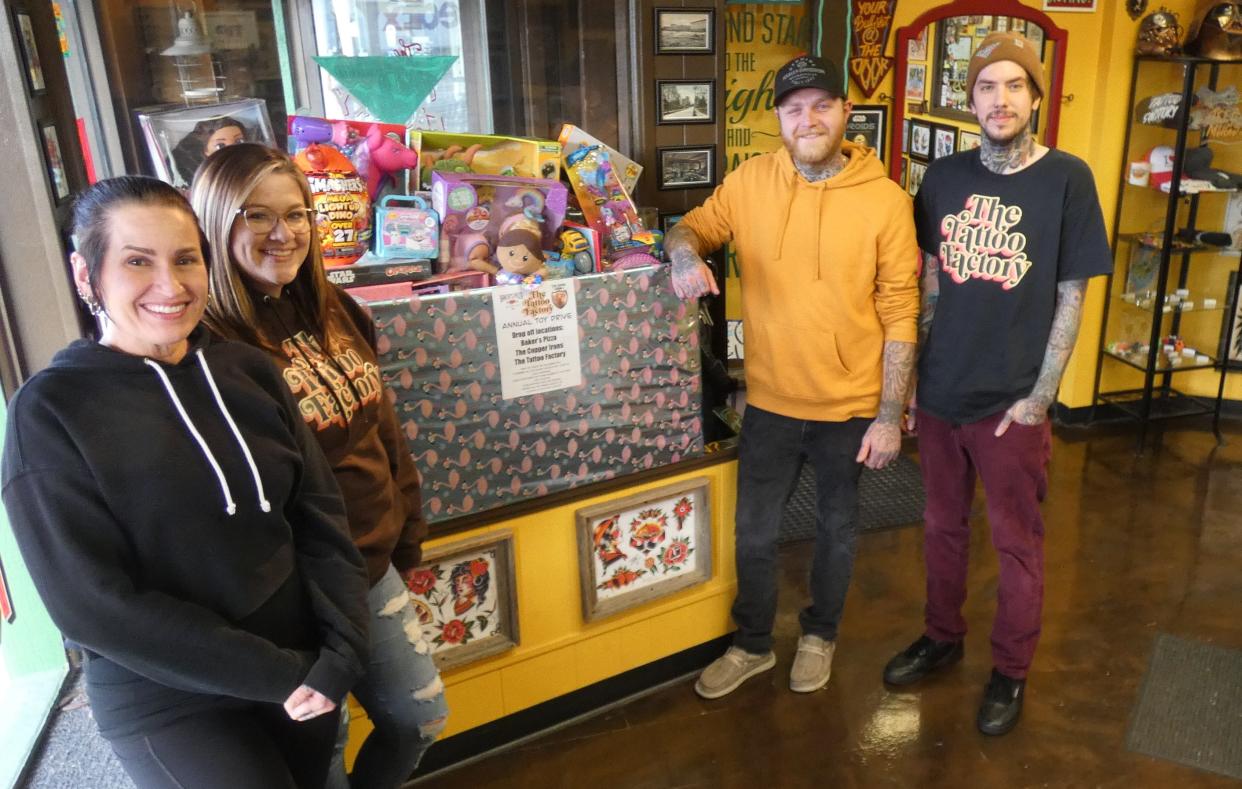 Tori Robinson, Brittany Potter, Brenton Potter and Matt Rister, from left, show off some of the toys that have been donated this year. The goal is to have The Tattoo Factory's entire front window filled with toys by the time the drive ends on Dec. 8.