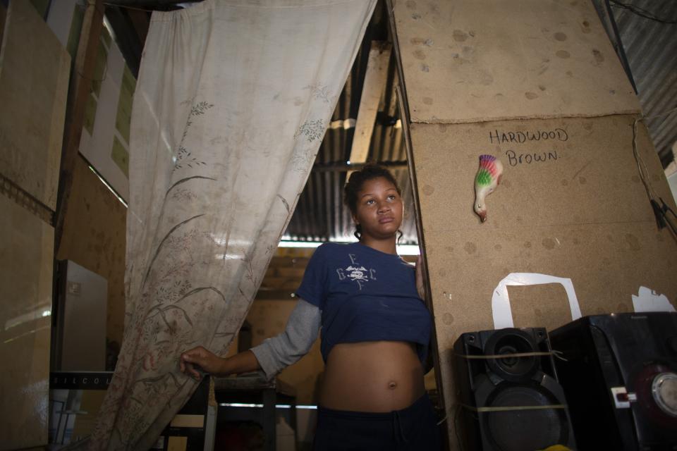 In this photo taken Aug. 5, 2019, 14-year-old Rosibeth Vargas, who is seven months pregnant, stands in her home where she lives with her parents, 18-year-old sister and nephew, in the Tablitas area of the Caucaguita neighborhood on the outskirts of Caracas, Venezuela. Vargas said her school allows student mothers to bring their children to class, but that she dropped out after being bullied. (AP Photo/Ariana Cubillos)