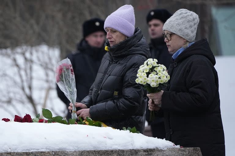 Las mujeres depositan flores para rendir homenaje a Alexei Navalny en el monumento, una gran roca de las islas Solovetsky, donde se estableció el primer campo del sistema de prisiones políticas Gulag, cerca del histórico edificio del Servicio Federal de Seguridad (FSB, sucesor de la KGB soviética) en Moscú, Rusia, el 24 de febrero 