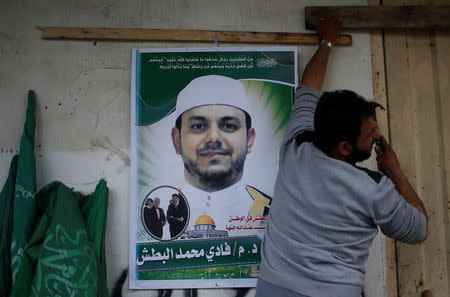 A man hangs a poster depicting Palestinian electrical engineer Fadi al-Batash, who was shot to death in Malaysia, on his family house in the northern Gaza Strip April 21, 2018. REUTERS/Mohammed Salem