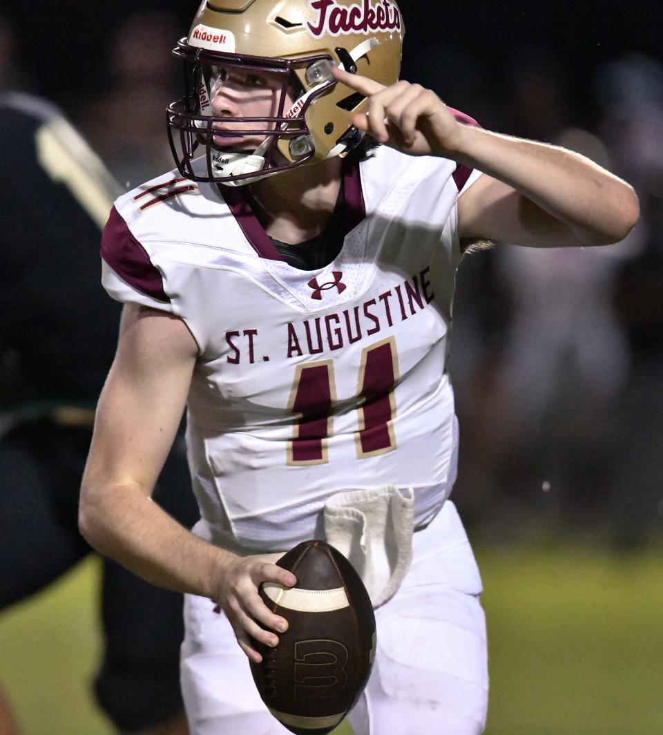 St. Augustine's quarterback Locklan Hewlett (11) signals for a receiver as he scrambles late in the first quarter. The St. Augustine Yellow Jackets traveled to Nease High School's Panther Stadium for Friday night's Saint Johns County high school football rivalry game October 6, 2023.