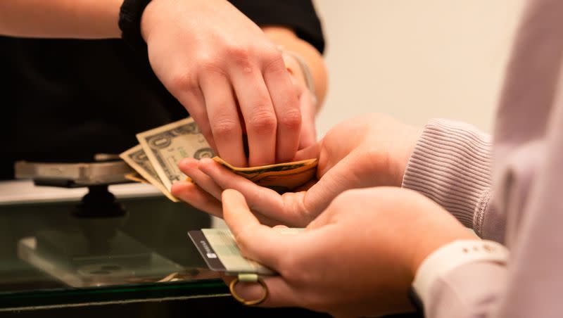 An employee gives change to a customer at Thread at City Creek Center in Salt Lake City on Friday, Nov. 24, 2023. An economic report predicts steady growth in the state in 2024.