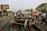 People gather at the site where a passenger train derailed injuring at least 100 people, near Banha, Qalyubia province, Egypt, Sunday, April 18, 2021. At least eight train wagons ran off the railway, the provincial governor's office said in a statement. (AP Photo/Fadel Dawood)