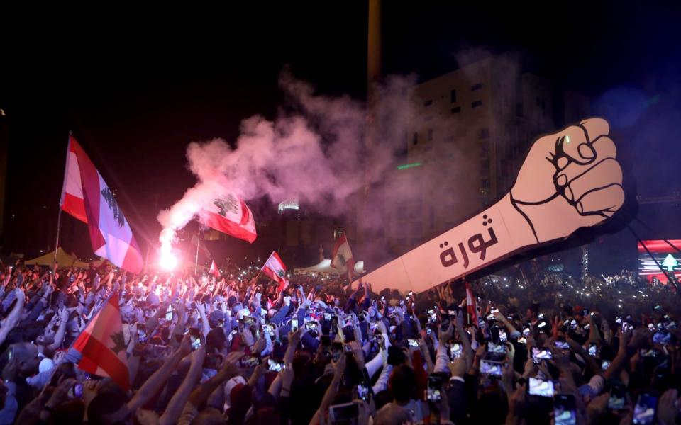 Lebanese demonstrators raise a giant fist bearing the Arabic word "revolution" in November 2019 - PATRICK BAZ/AFP via Getty Images