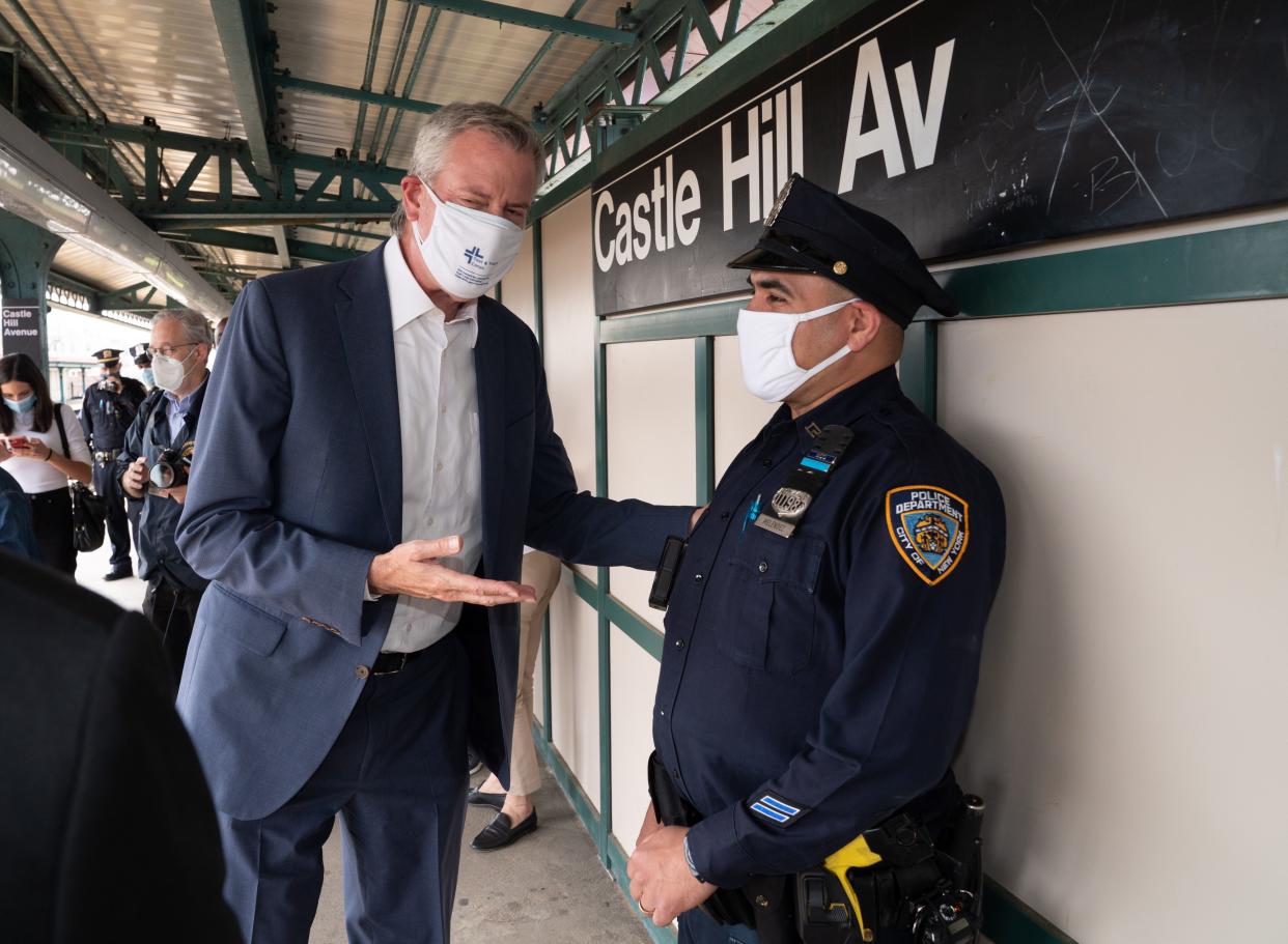 Mayor Bill de Blasio greets an NYPD officer at the Castle Hill Ave. subway station before catching a #6 train to Harlem on Friday, May 7, in the Bronx. 
