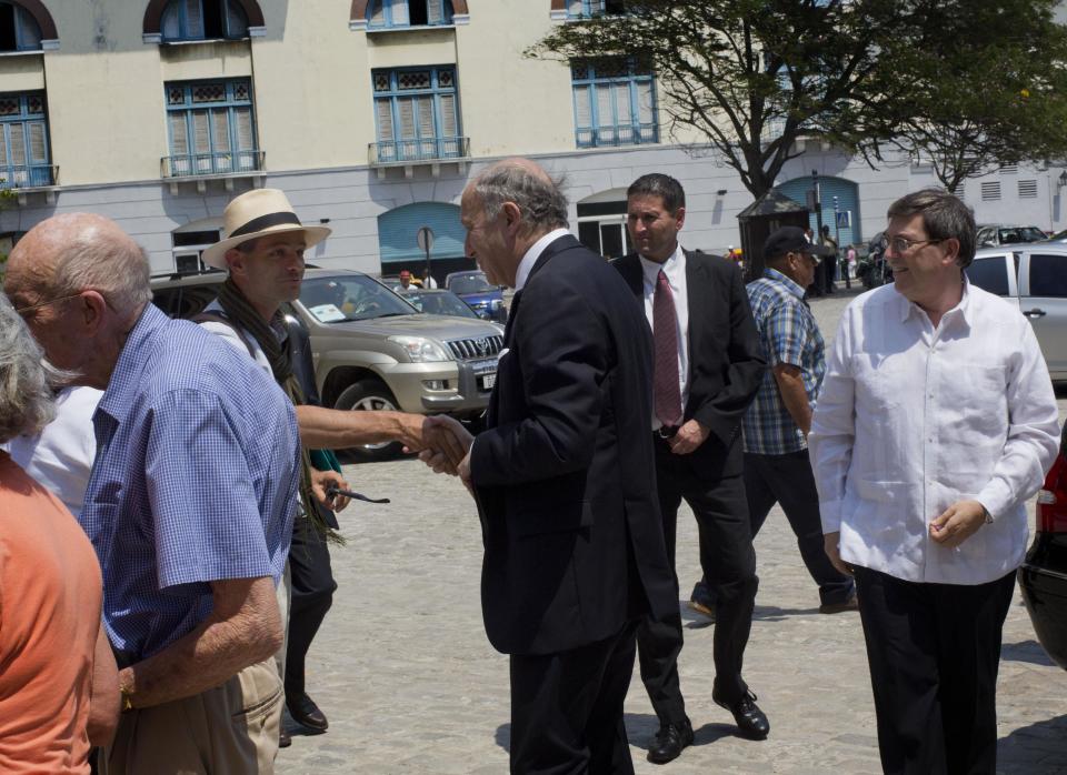 France's Foreign Minister Laurent Fabius, center, greets a tourist as Cuba's Foreign Minister Bruno Rodriguez, right, looks on in Havana, Cuba, Saturday, April 12, 2014. The French foreign ministry says Fabius will promote alliances between the two nations’ firms and support French companies that want to do business in Cuba. (AP Photo/Ramon Espinosa)