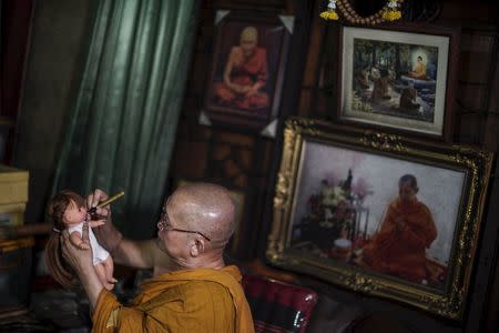 Buddhist monk Phra Winai Thidtapanyo, 64, anoints on a "child angel" doll during a blessing ritual at Wat Bua Khwan temple in Nonthaburi, Thailand, January 26, 2016. REUTERS/Athit Perawongmetha