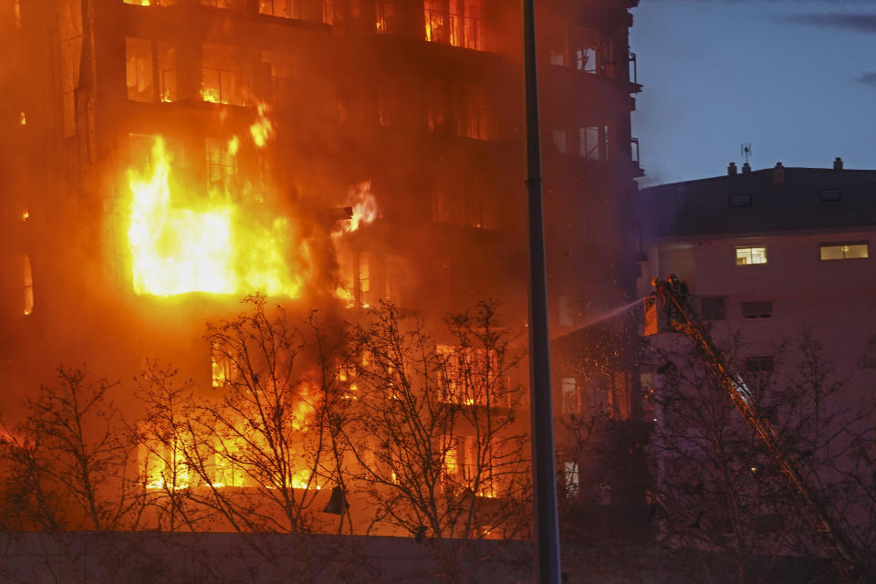 Firefighters spray water on a housing block as it burns in Valencia, Spain, Thursday, Feb. 22, 2024. The cause of the fire is unknown and if there are any victims. (AP Photo/Alberto Saiz)