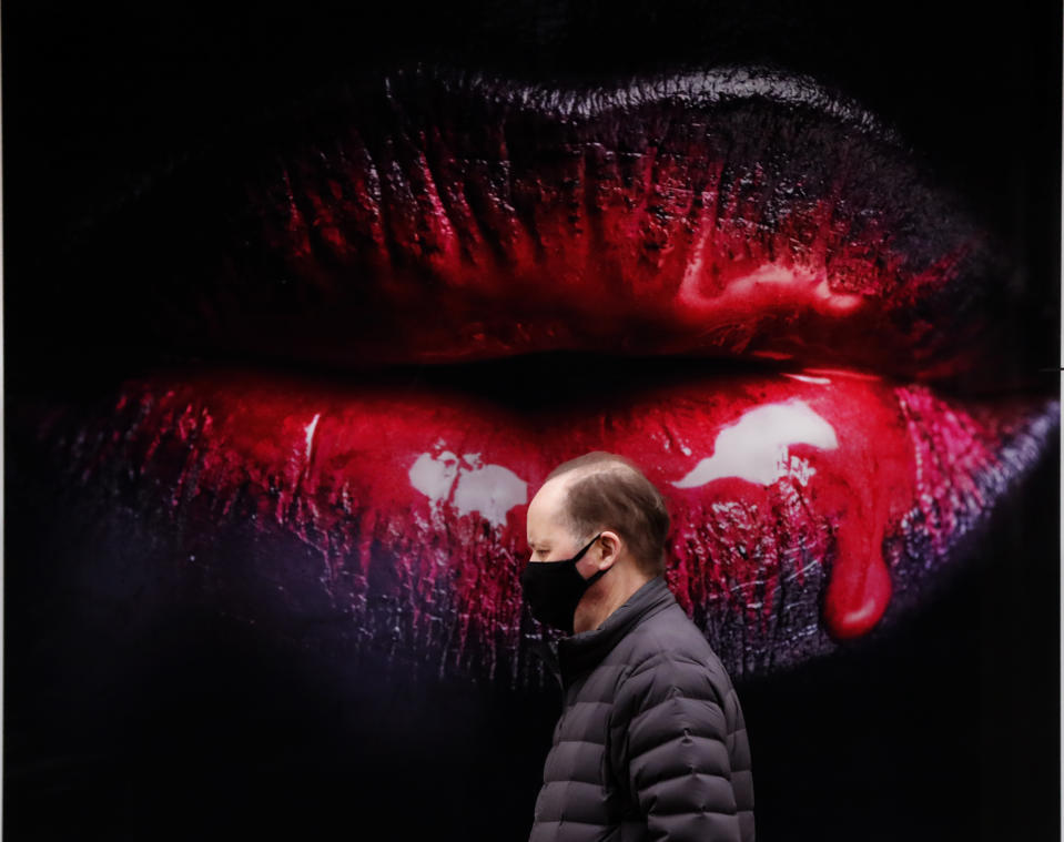 <p>A man wearing a face covering due to the COVID-19 pandemic walks past a poster in a shop in London, Wednesday, Feb. 17, 2021. (AP Photo/Frank Augstein)</p>
