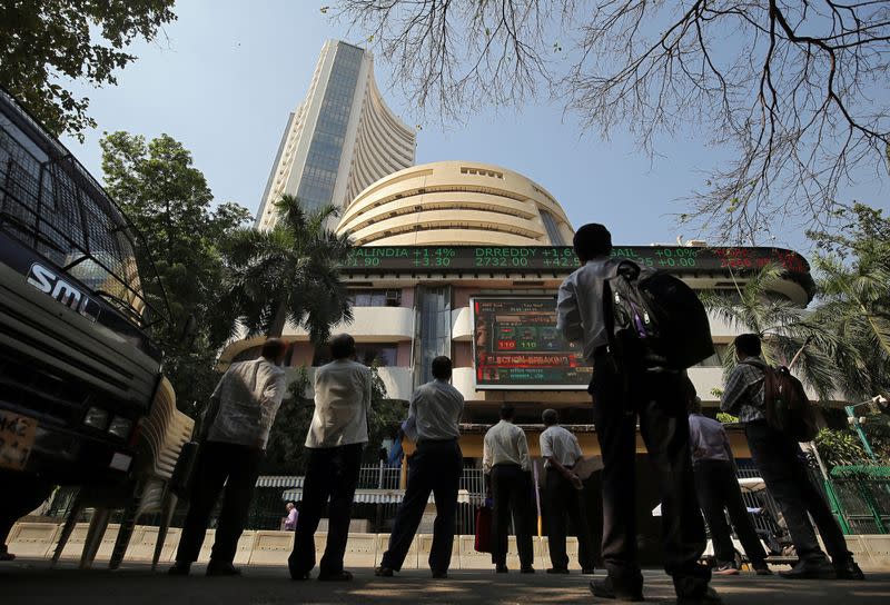 People look at a screen displaying the Sensex results on the facade of the Bombay Stock Exchange (BSE) building in Mumbai