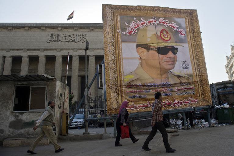 Egyptians walk past a huge poster of armed forces chief General Abdul Fatah Al-Sisi outside the High Court in downtown Cairo, on March 27, 2014