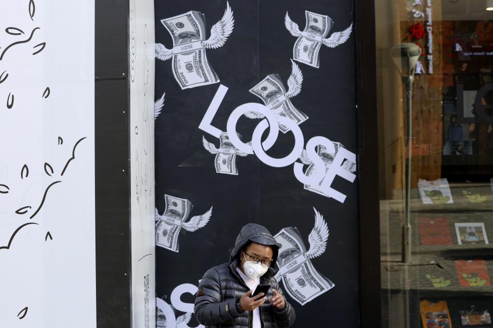 A man stands near a billboard depicting bundles of flying U.S. dollars at a retail district in Beijing, China, Tuesday, Nov. 27, 2018. Asian markets clocked more gains Tuesday ahead of a meeting between the U.S. and China at the Group of 20 summit this week, despite President Donald Trump's comments that it's "highly unlikely" he'll hold off on raising tariffs as Beijing requested. (AP Photo/Ng Han Guan)