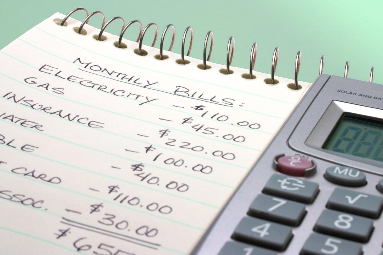 Closeup of monthly expenses written on notepad and a calculator