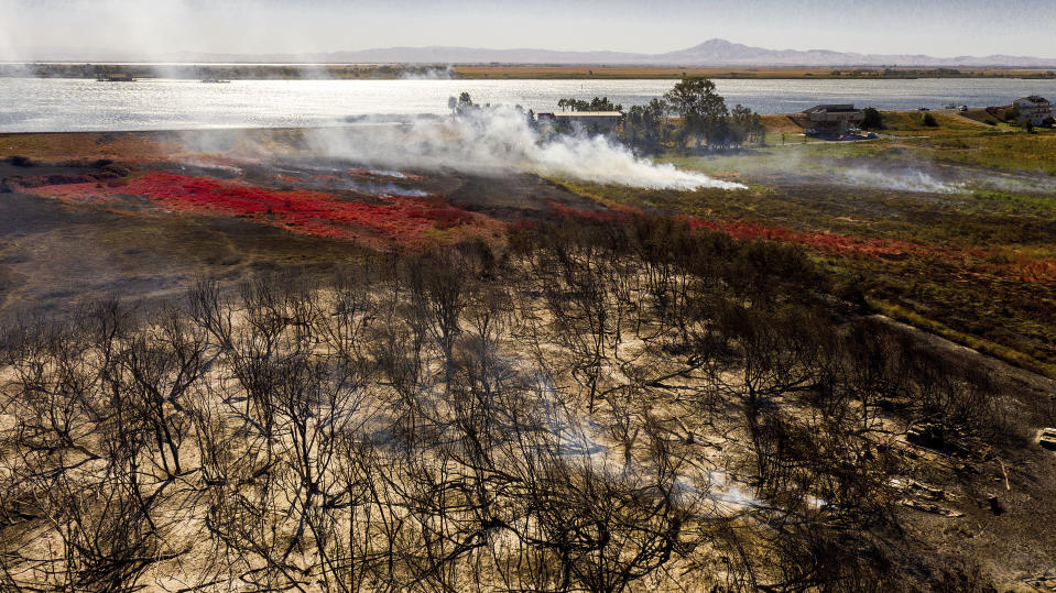 Scorched land lines a plot on Brannan Island following the Brannan Fire in Sacramento County, Calif., on Tuesday, Oct. 12, 2021. Fueled by dry, strong winds, the blaze leveled dozens of residences on Monday afternoon. (AP Photo/Noah Berger)