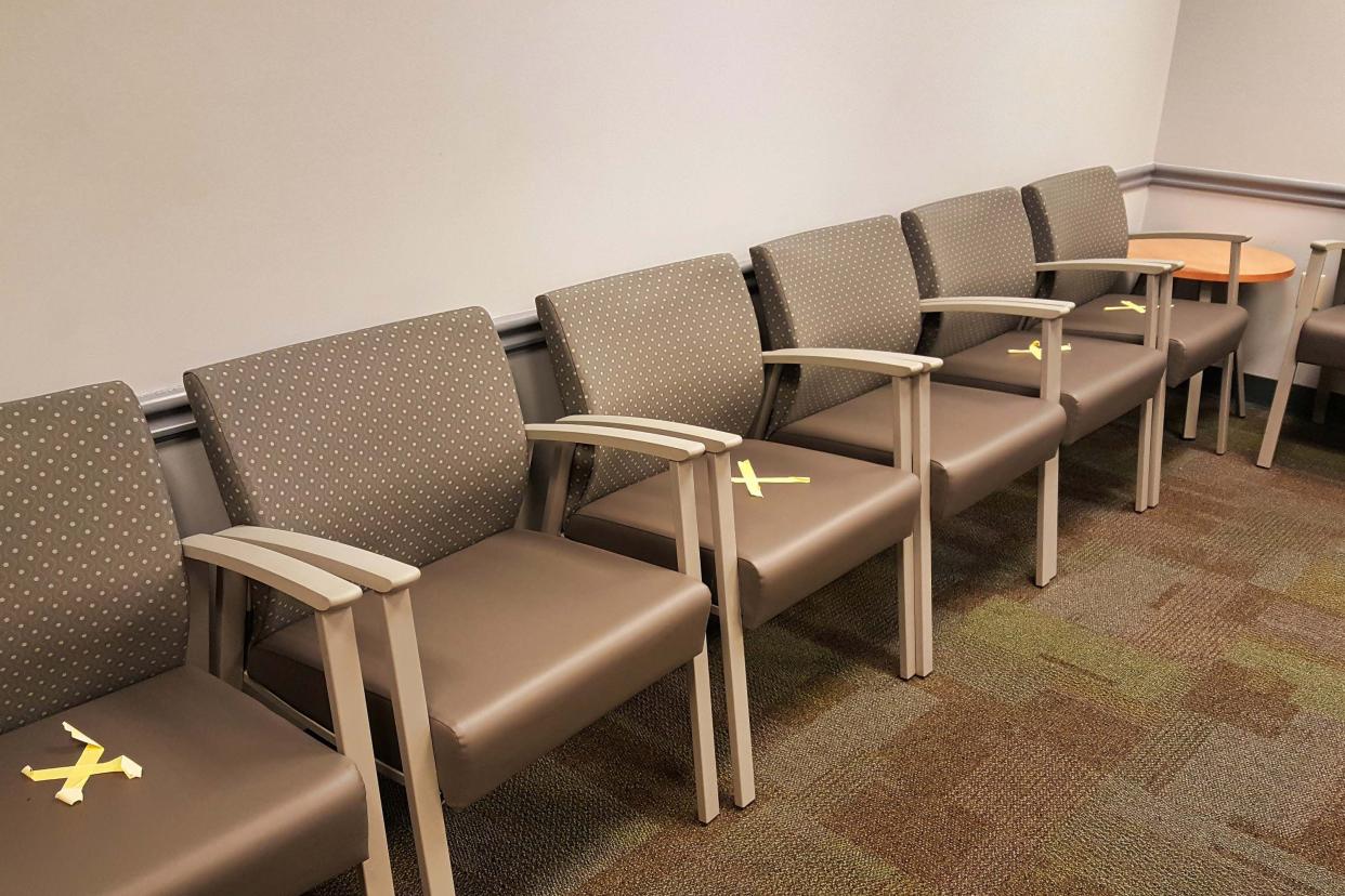 tape X's marking where patients shouldn't sit to maintain a six foot distance between each other, at a local doctors office