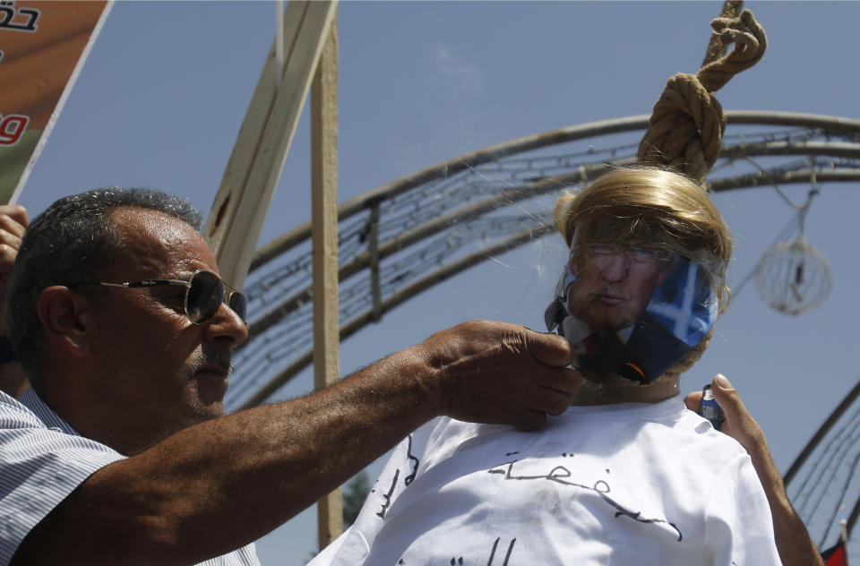 A Palestinian burns an effigy of the US President Donald Trump aduring a protest against the American-led Mideast peace conference in Bahrain, in the West Bank city of Bethlehem, Tuesday, June 25, 2019.(AP Photo/Majdi Mohammed)